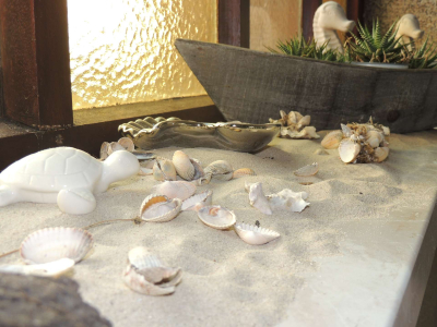 Sand und Muscheln als Dekoration auf Fensterbank
