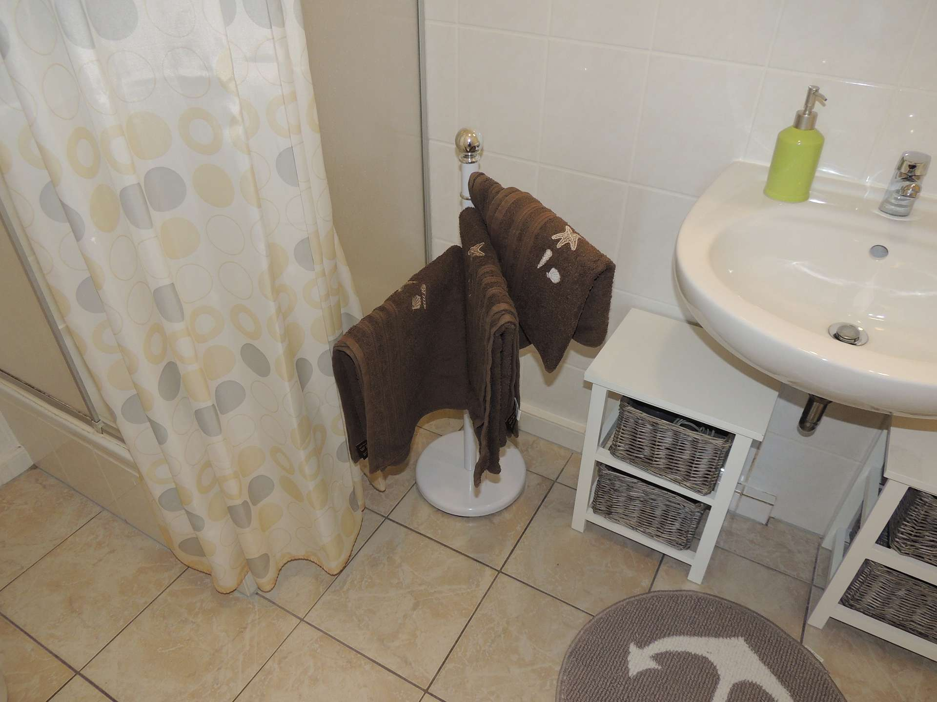 Badezimmer mit Dusche, Handtuchhalter, Waschbecken und Waschbeckenunterschränken