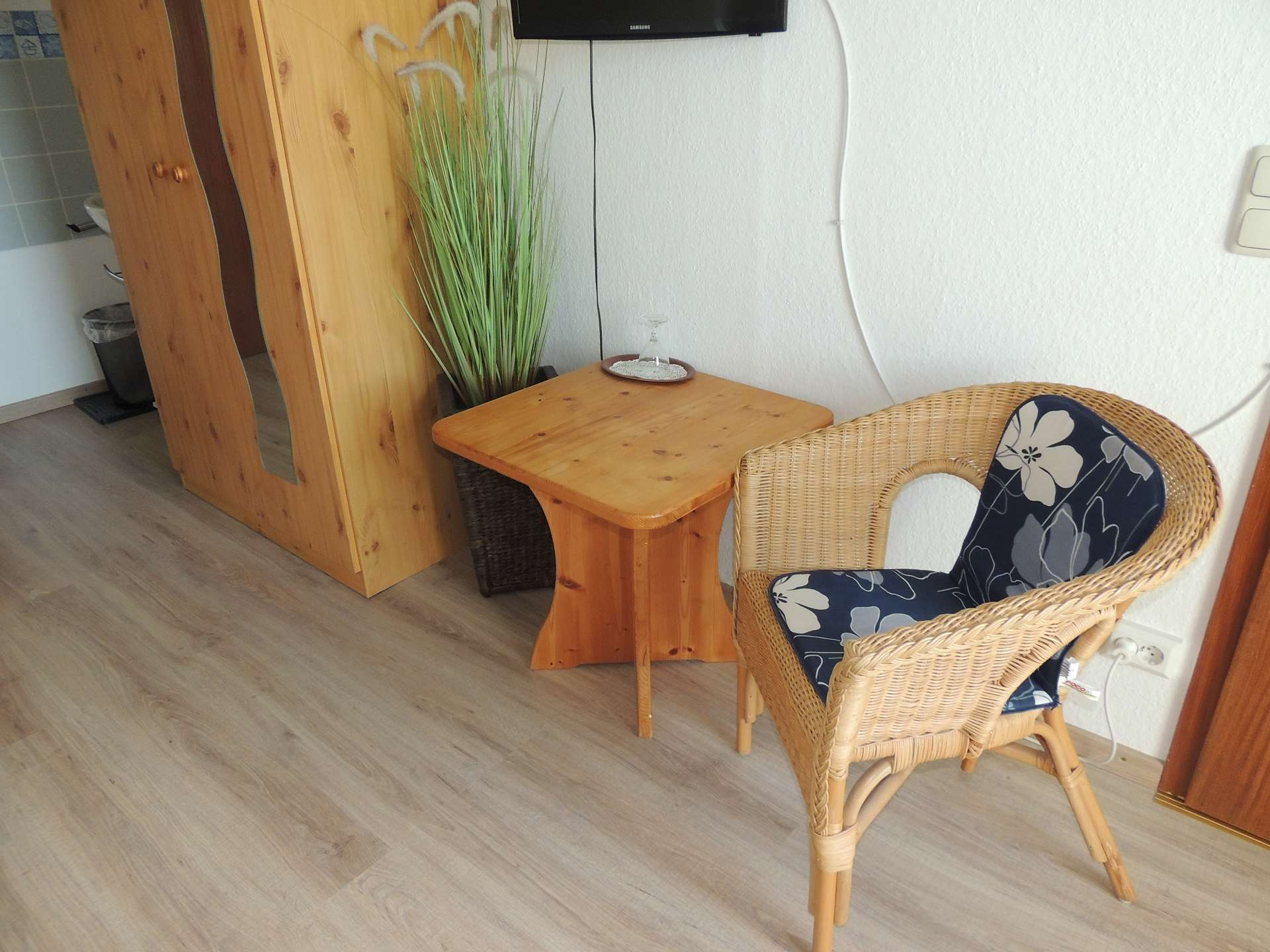 Wand mit Schrank, Tisch und Korbsessel