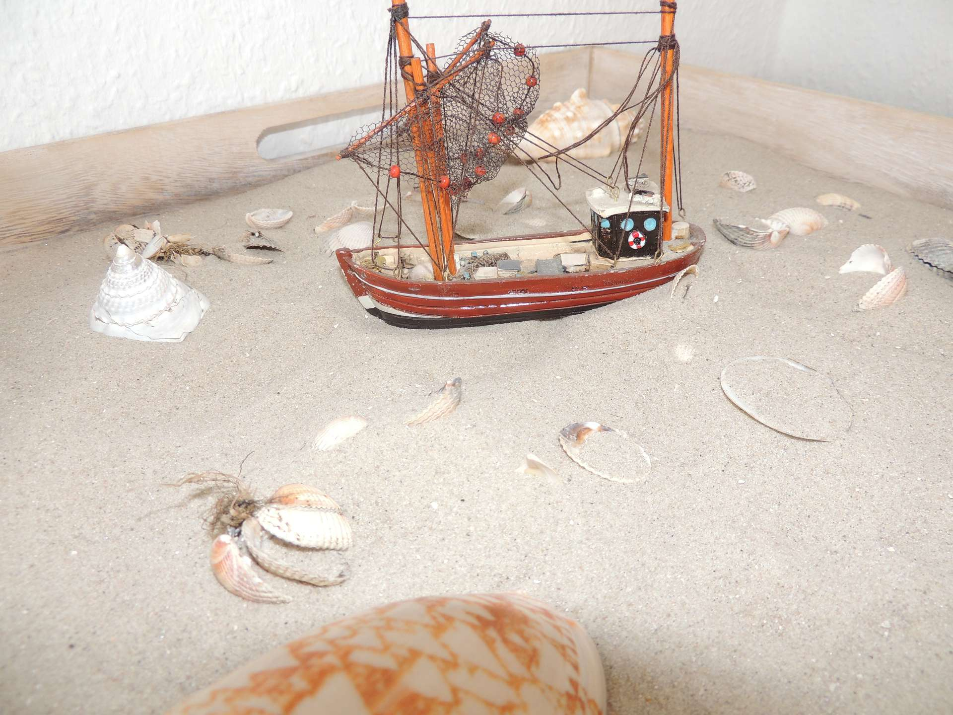 Dekoration - Sand mit Muscheln und Modellbauschiff mit zwei Masten
